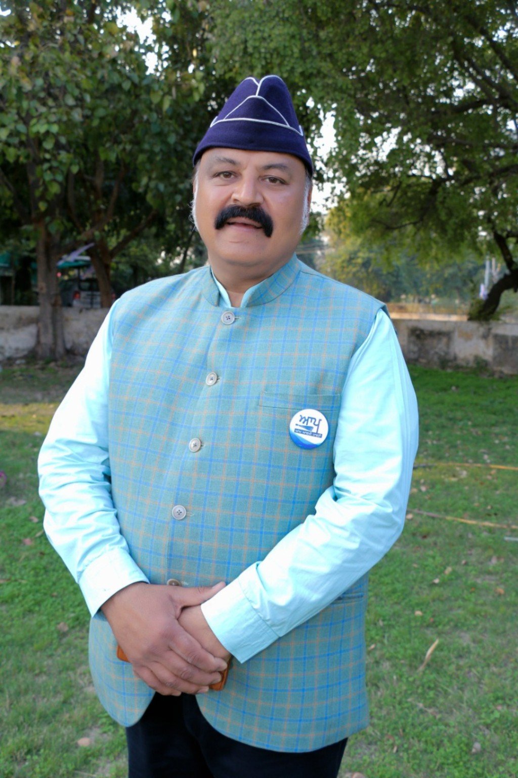 Dr Harish Kant Walia outdoors wearing a blue waistcoat and cap